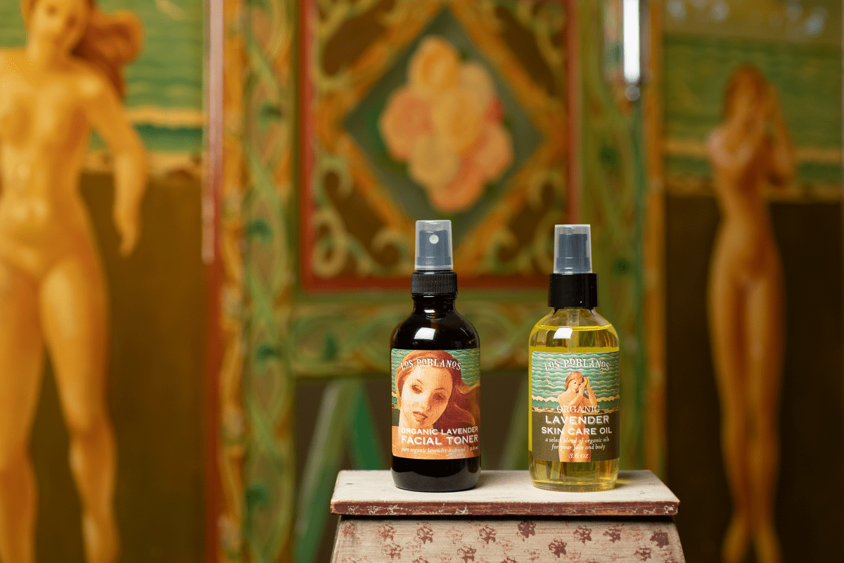 Two bottles of lavender oil on a decorative stand with classical painting in the background