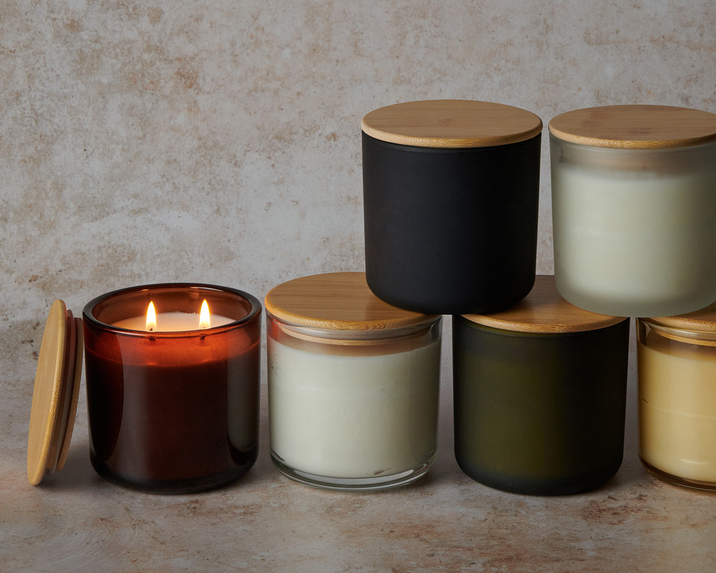Set of candles with wooden lids on a textured surface