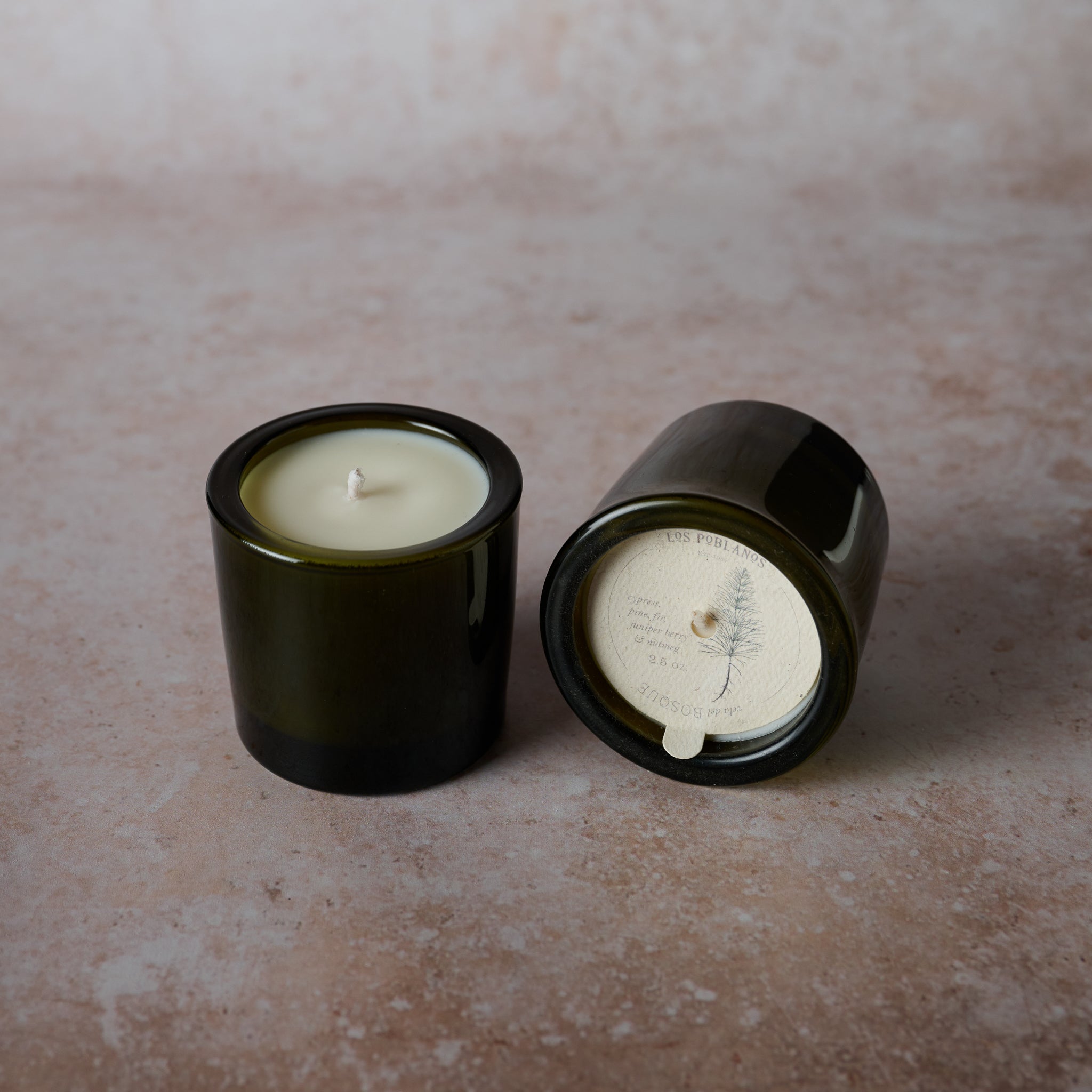 Two black candle holders with candles on a textured surface
