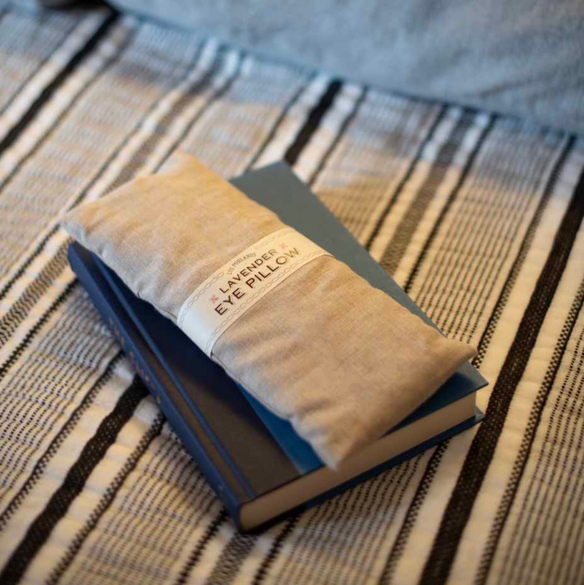 lavender eye pillow on top of a made bed with a book | Lavender Eye Pillow | Los Poblanos Shop