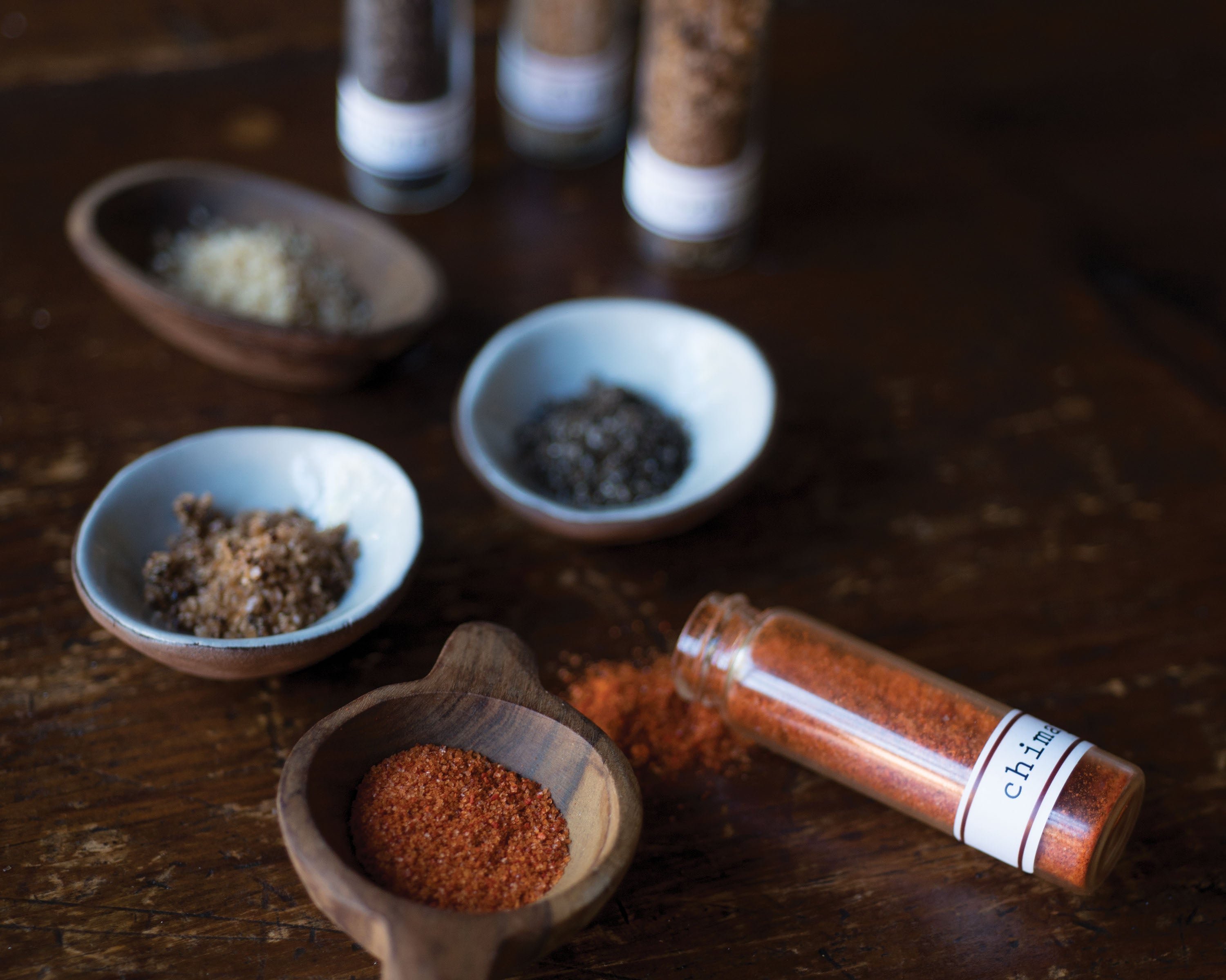 Spices in small bowls and containers on a wooden surface