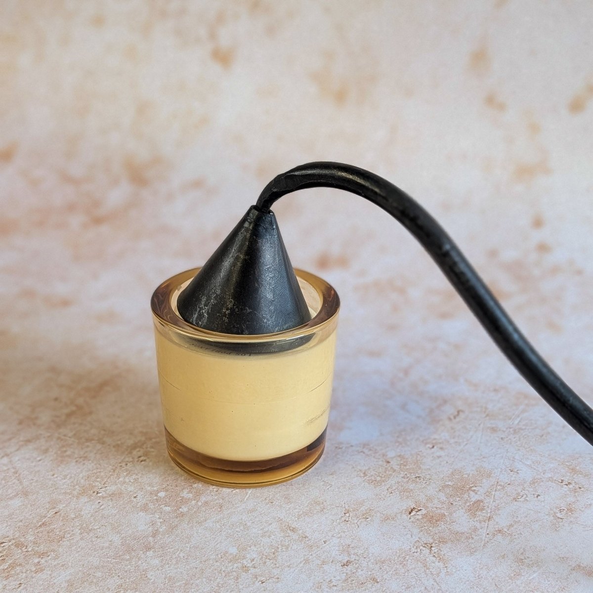 Metal candle snuffer on a beige candle