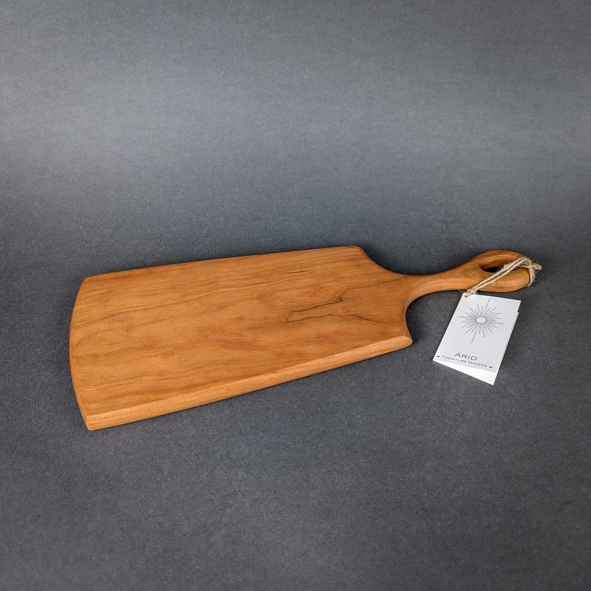 Handcrafted wooden charcuterie board featuring an ergonomic handle and natural wood grain.