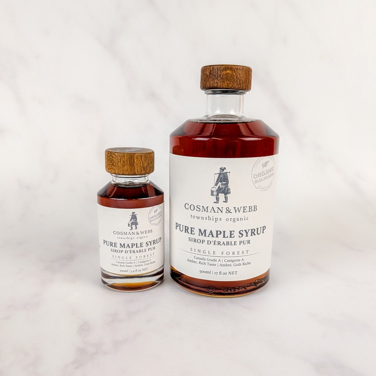 Two bottles of Cosman & Webb pure maple syrup on a light gray background