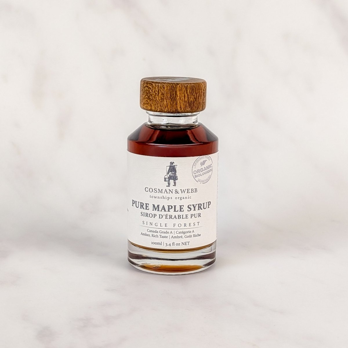 Small bottle of Cosman & Webb pure maple syrup on a light gray background