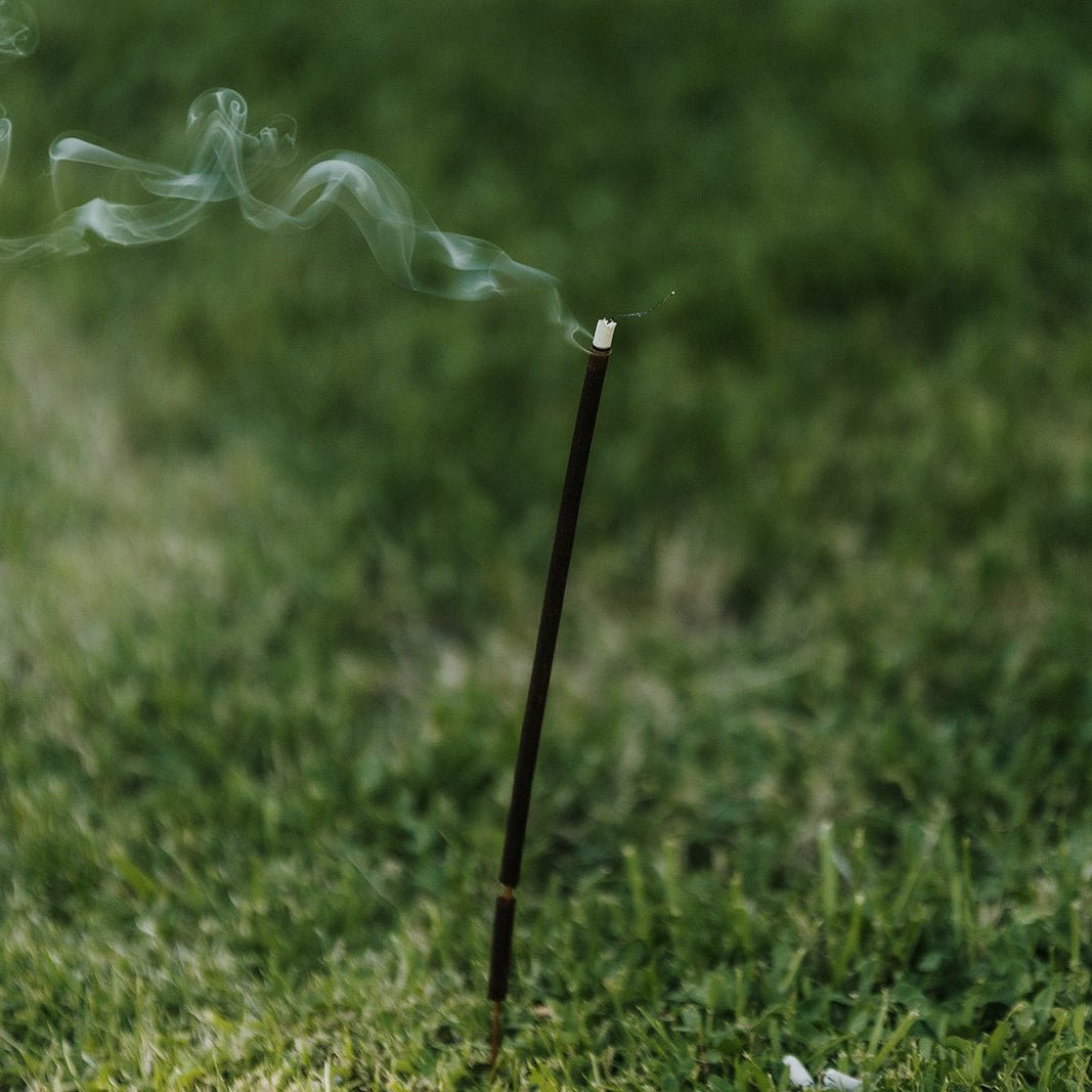 Incense stick with smoke on grass