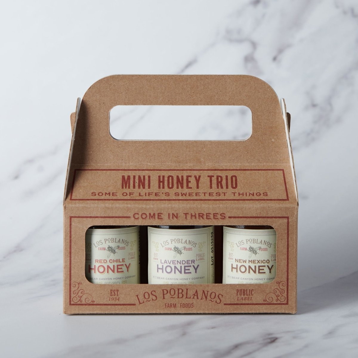 Mini honey trio packaging with three jars of honey on a marble surface