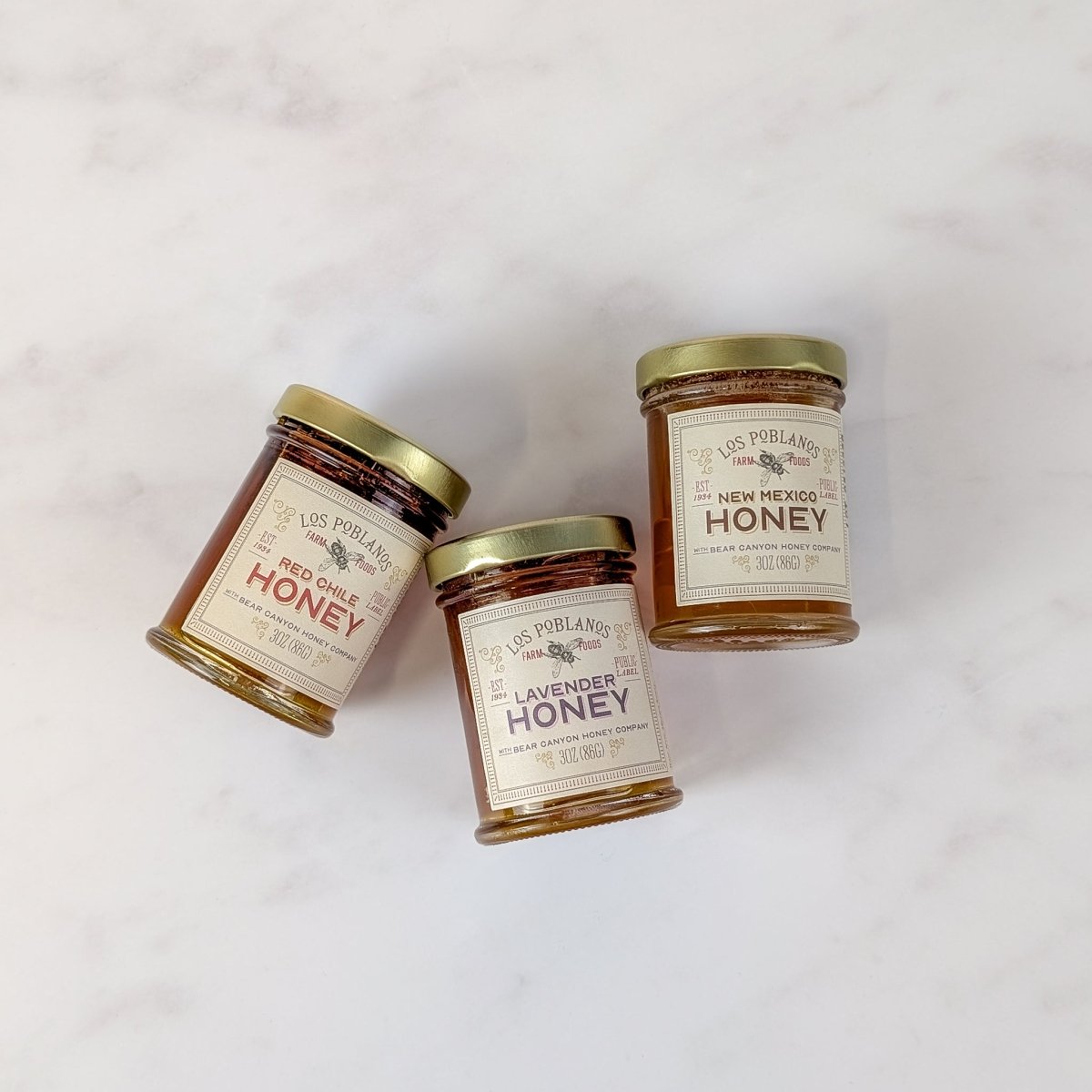 Three jars of honey from Los Poblanos on a white background