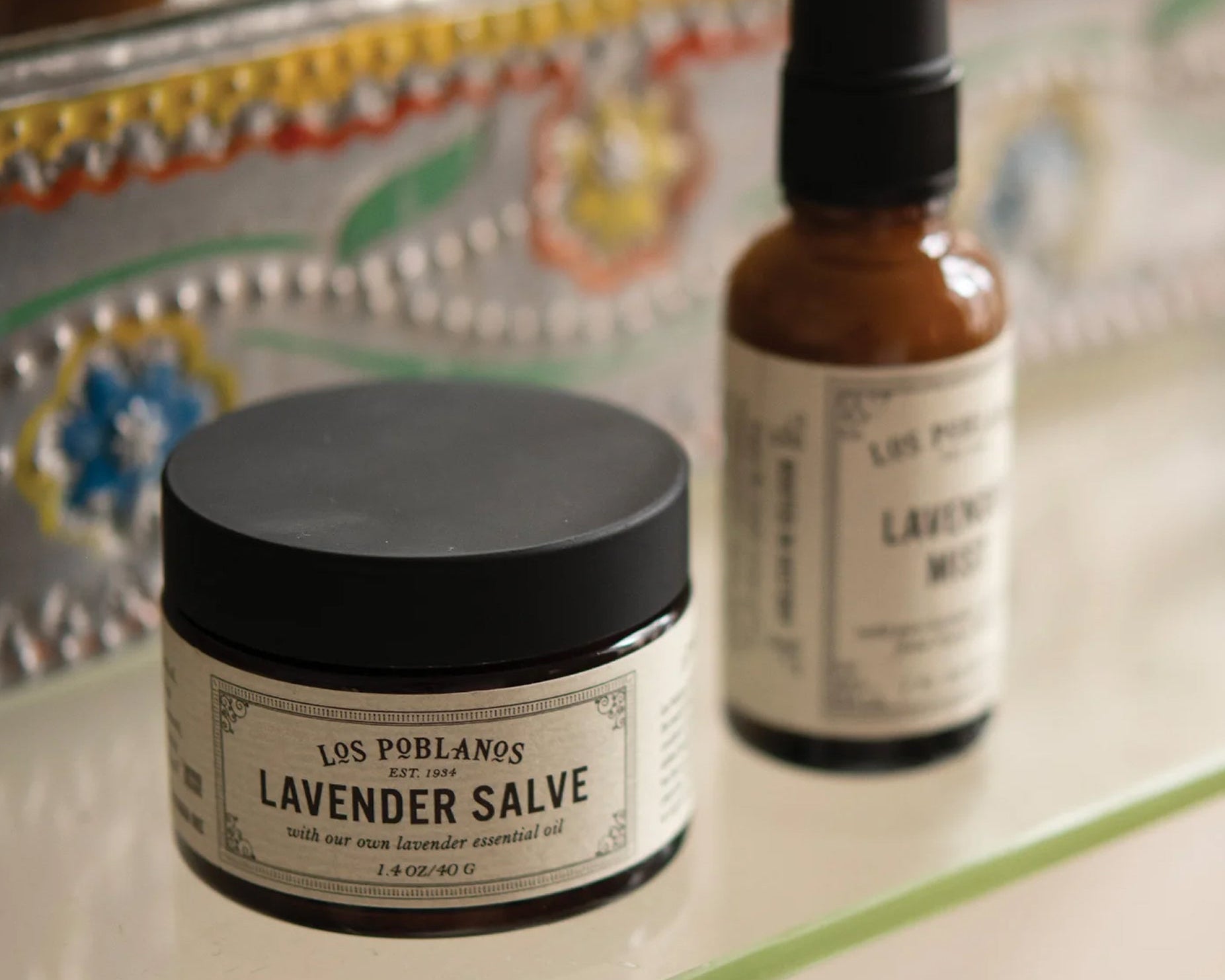 Los Poblanos Lavender Salve jar and bottle on a decorative surface