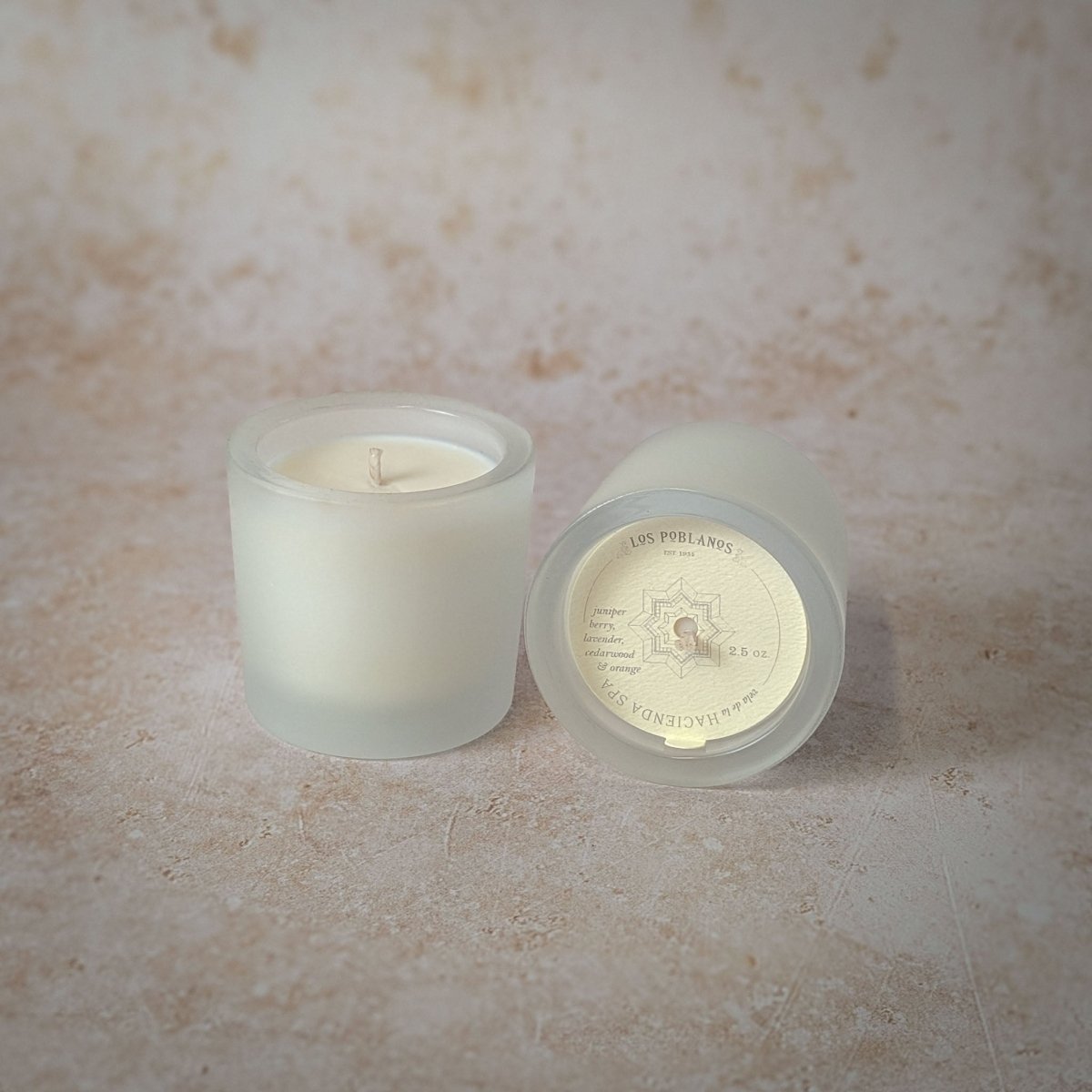 Two frosted glass candles on a textured surface