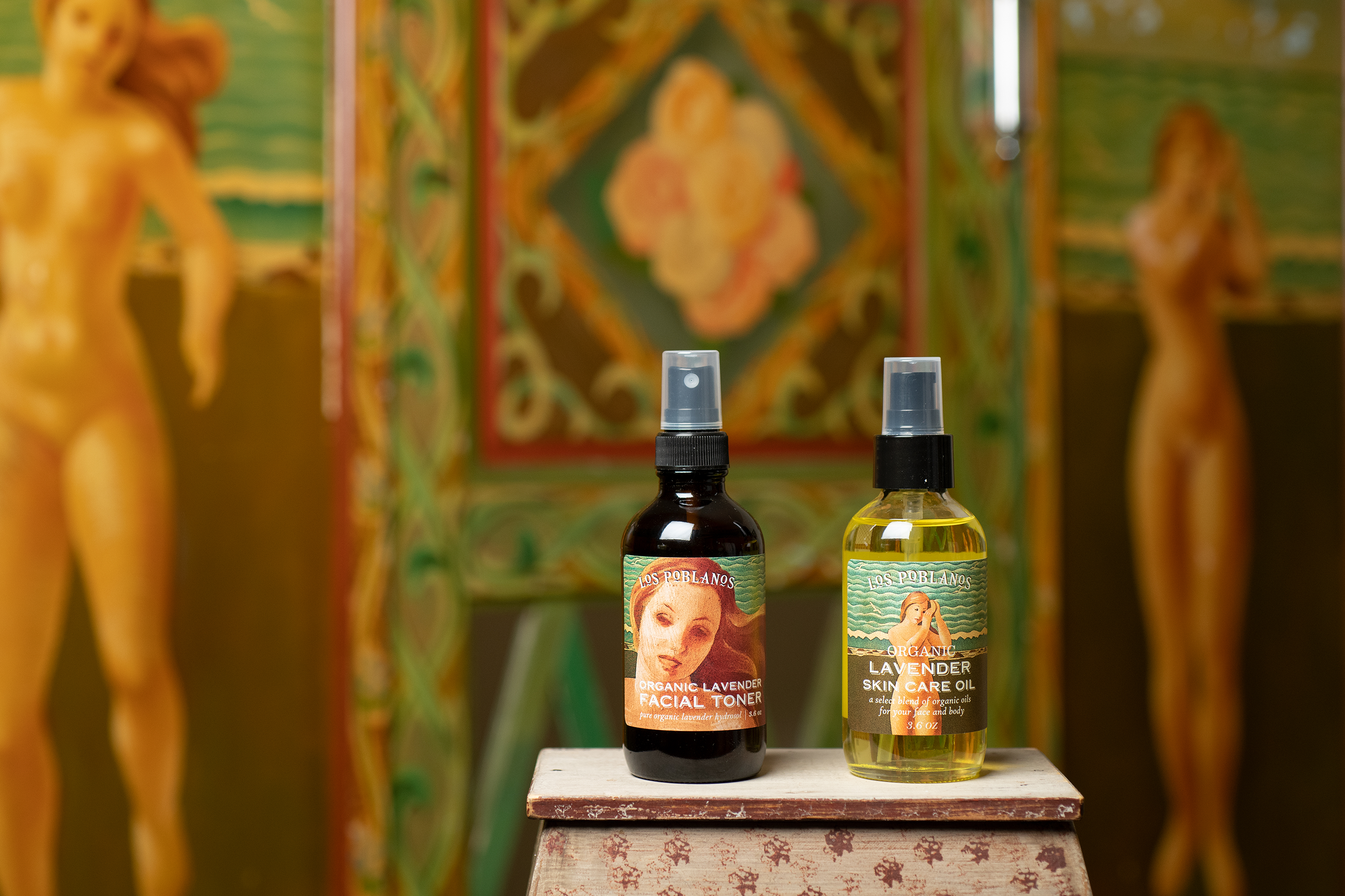 Two bottles of lavender oil on a decorative stand with classical painting in the background
