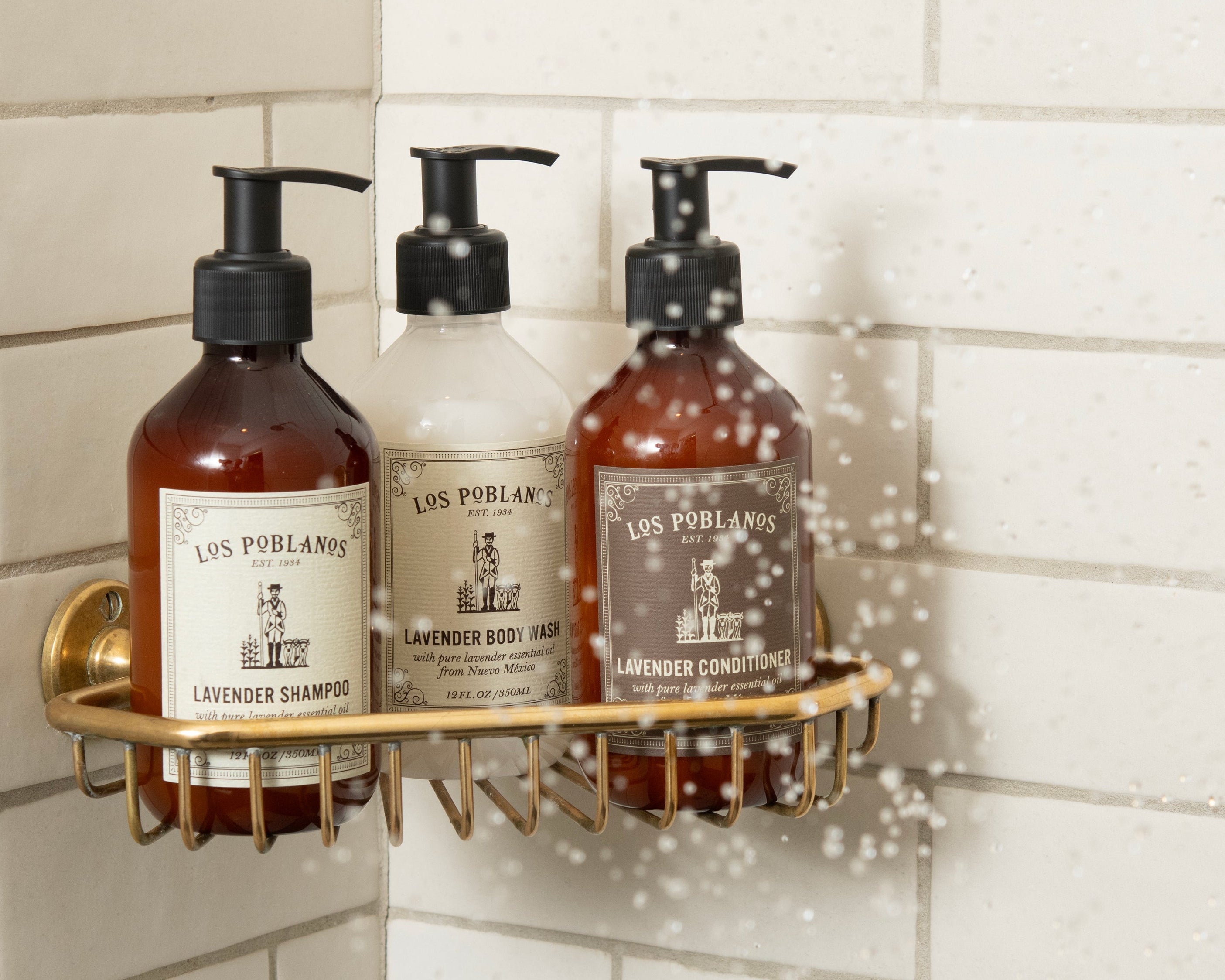 Three bottles of Los Pollos Hermanos products on a shower caddy with a tiled bathroom background.