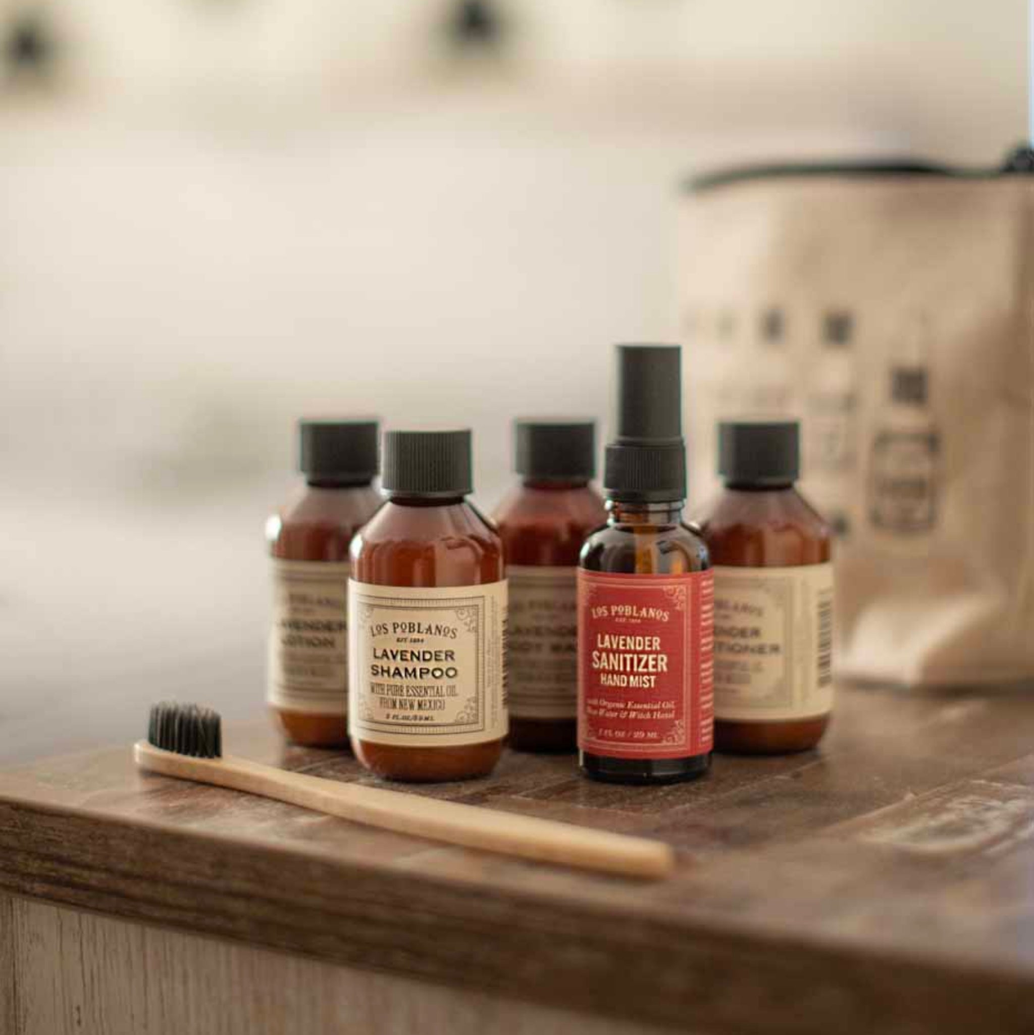 Set of travel sized lavender hair care products on a wooden surface with a blurred background