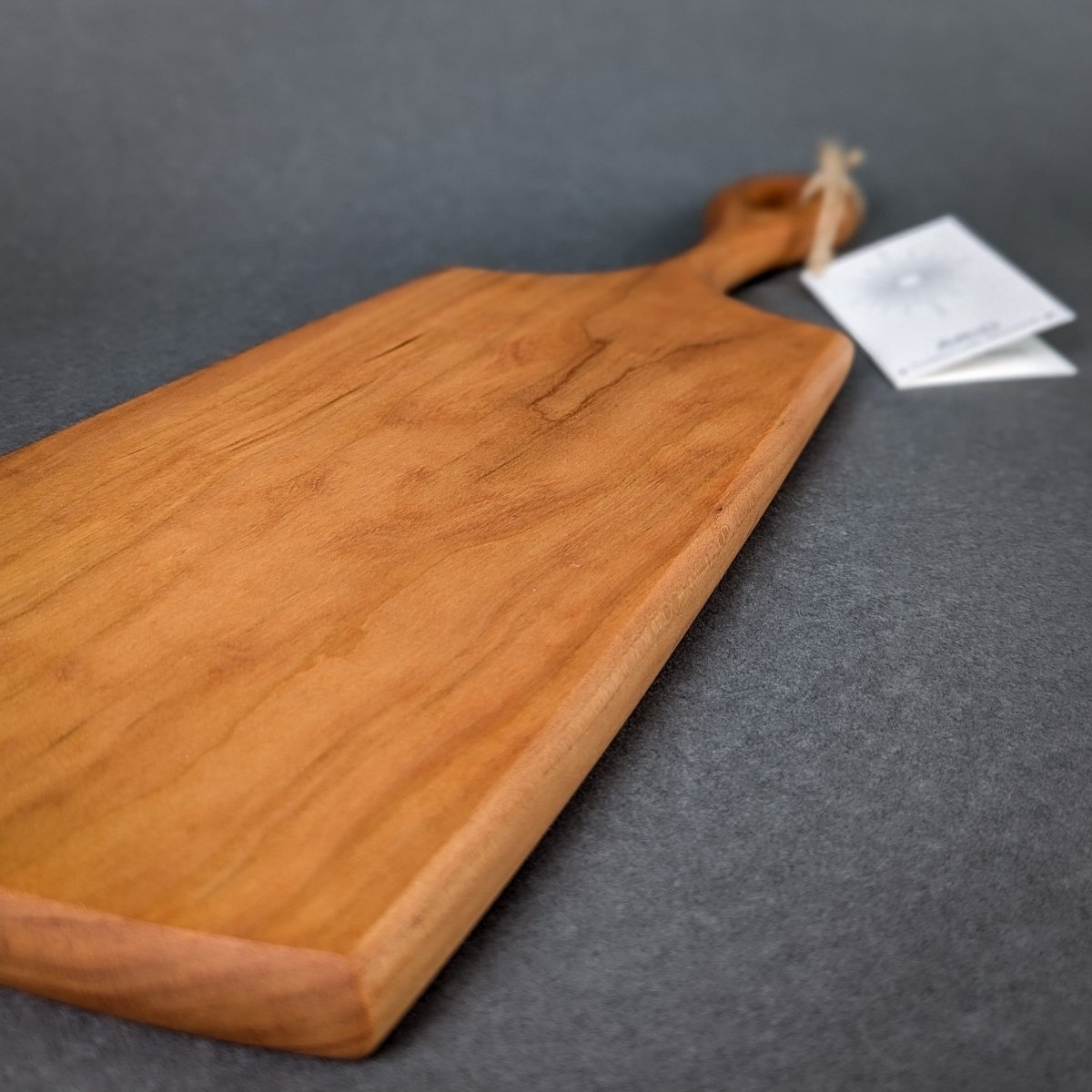 Handcrafted wooden charcuterie board featuring an ergonomic handle and natural wood grain.