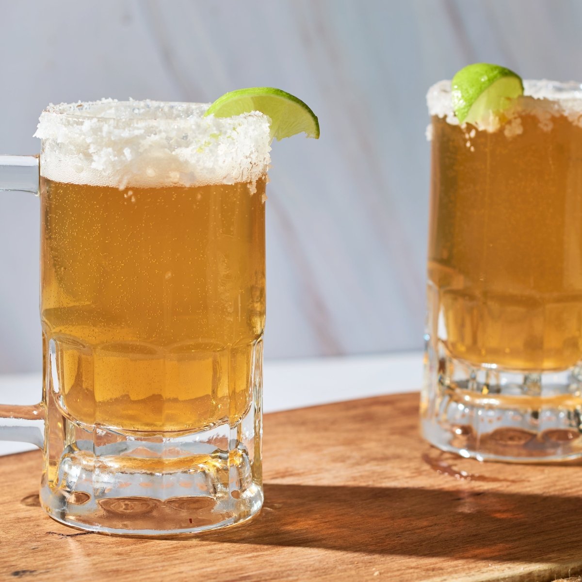 beer mugs with lime on wooden board