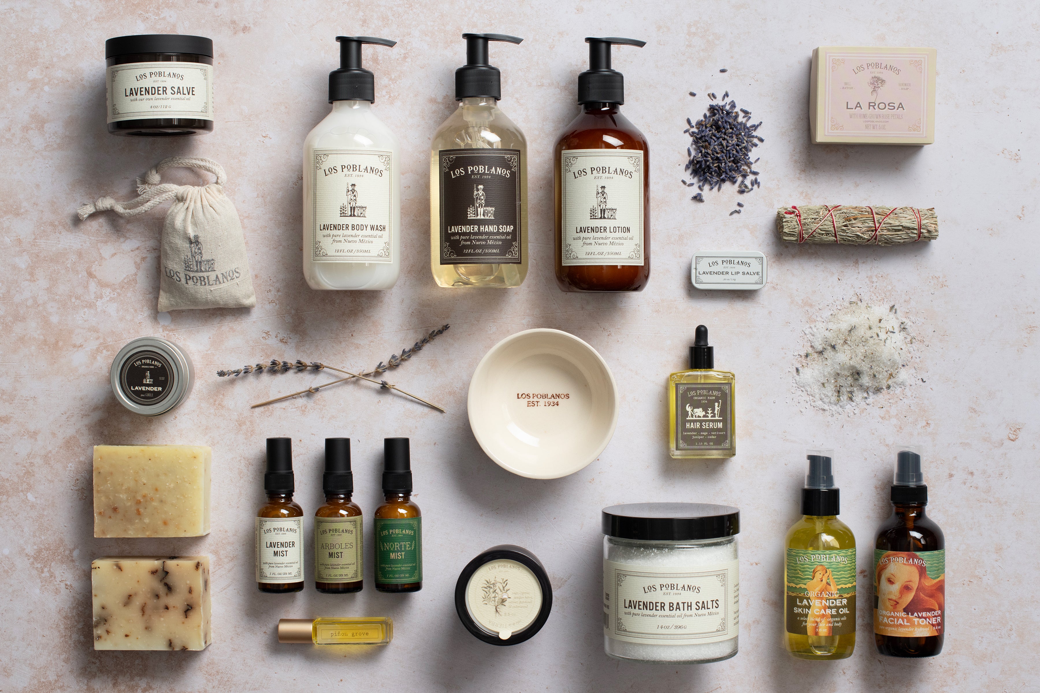 Collection of various skincare and wellness products on a textured surface with lavender flowers.