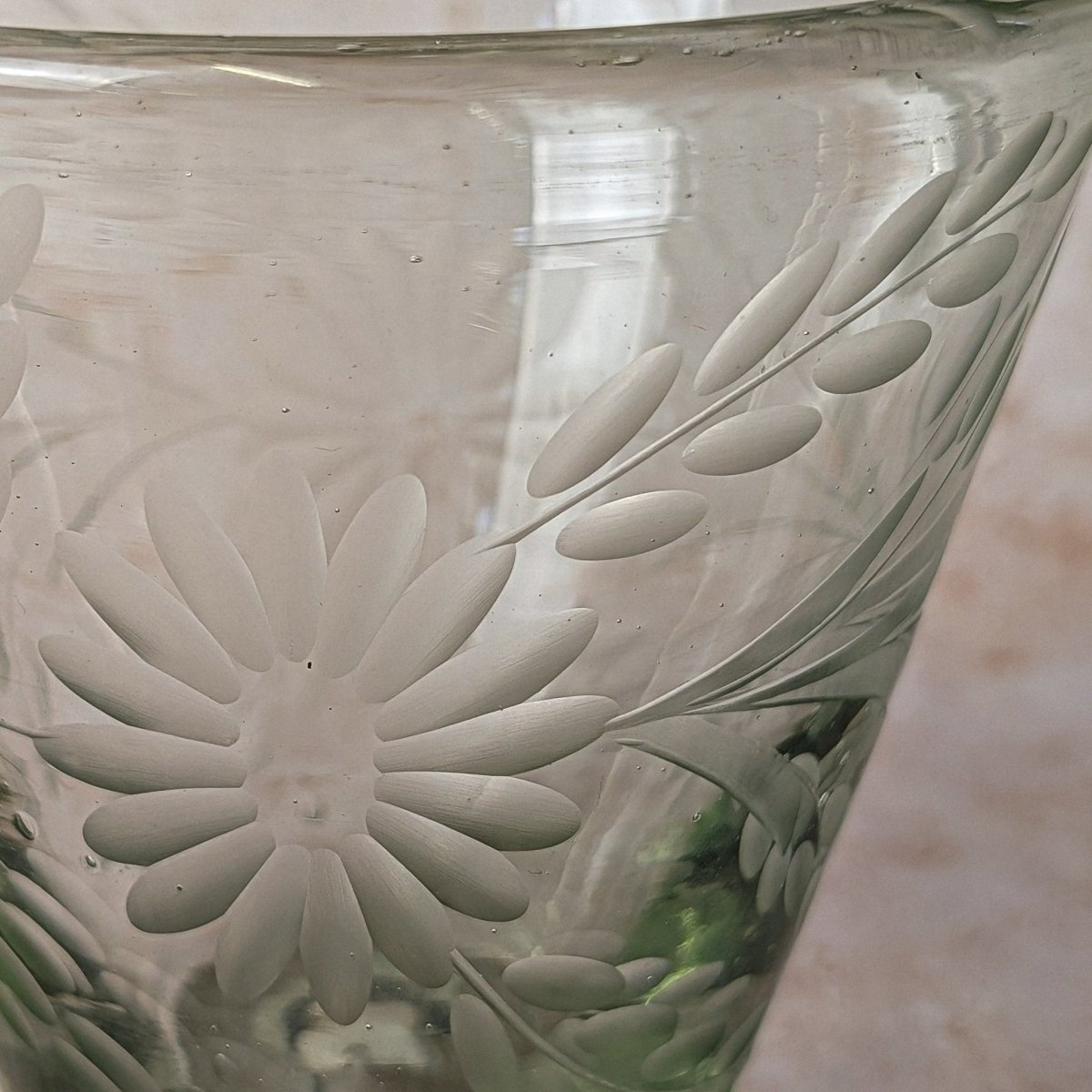 Close-up of a glass vase with floral embossing on a neutral background