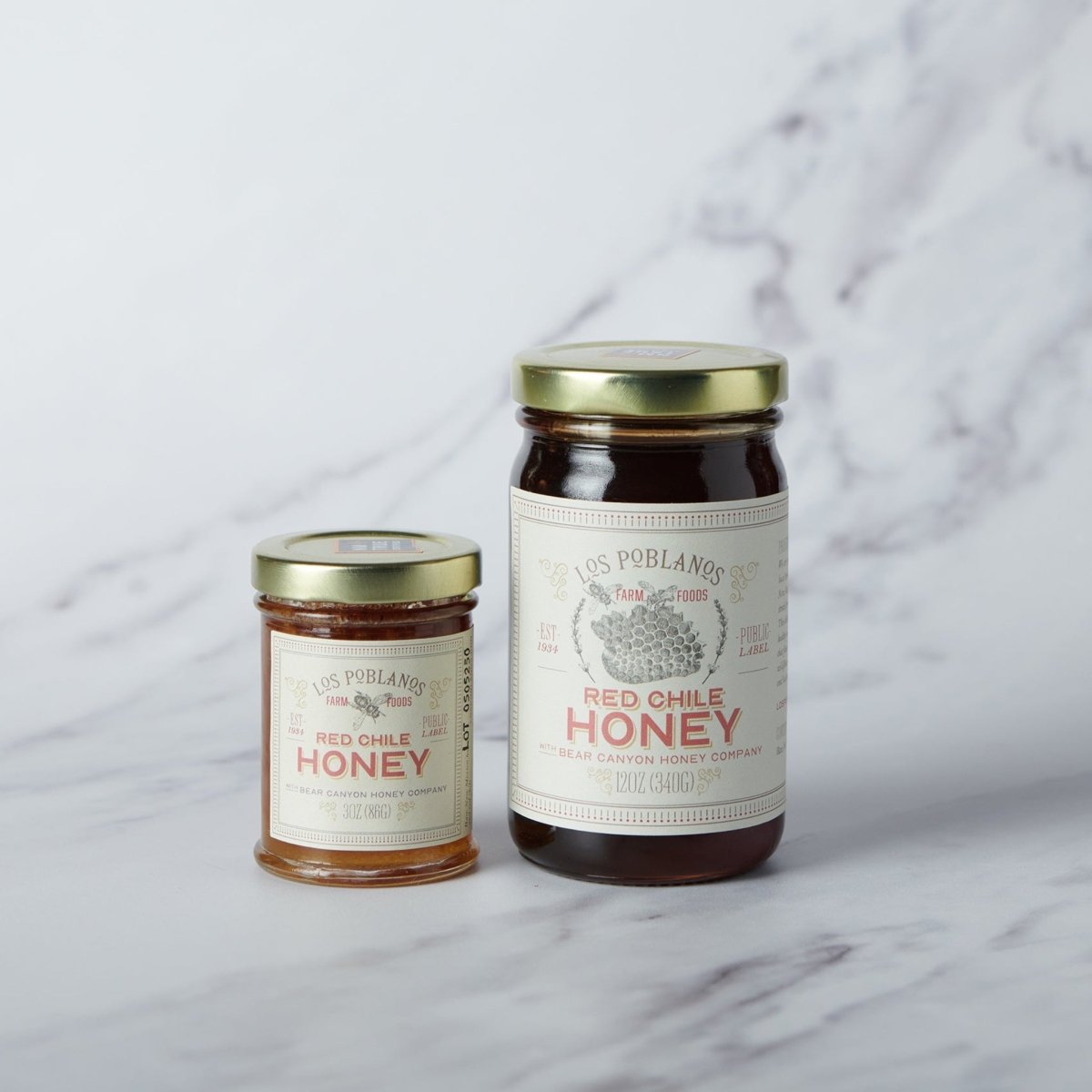 Two jars of Los Poblanos Red Chile Honey on a marble surface
