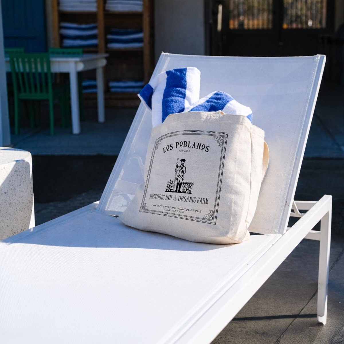 White bag with 'Los Poblanos' branding on a white chair outdoors.