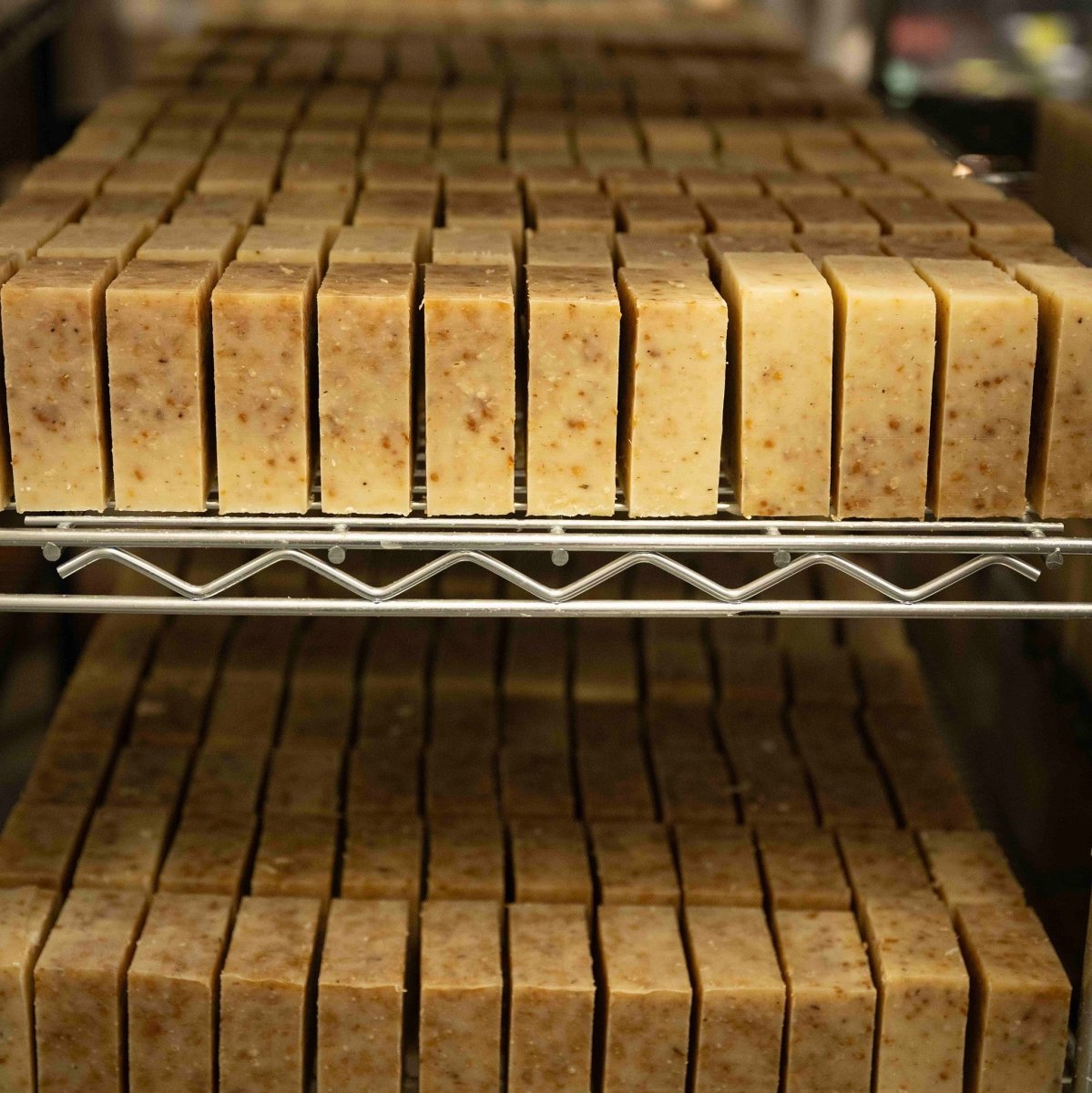 Rows of soap bars on a metal rack with a blurred background