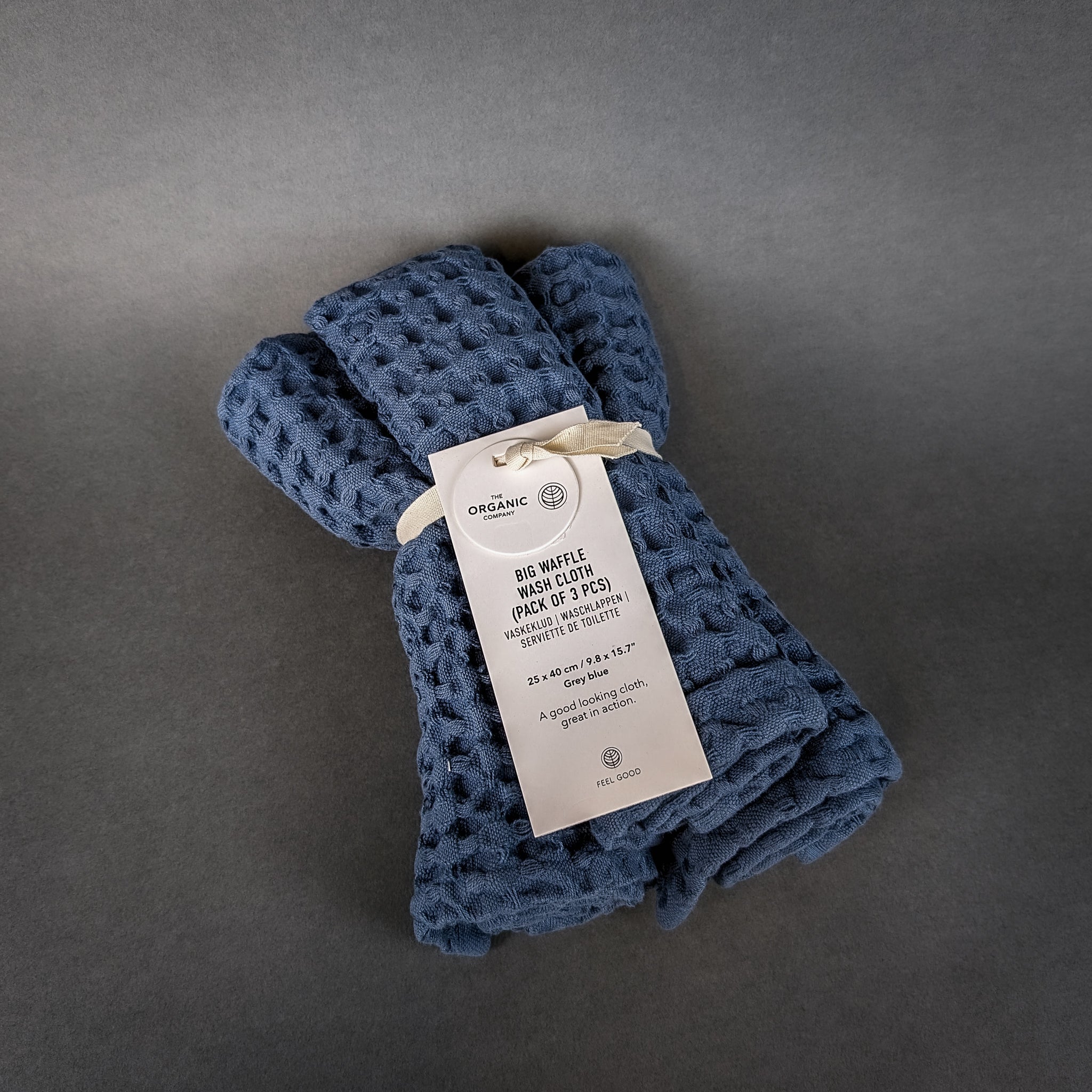 Folded blue waffle blanket with a tag on a gray background